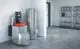 Viessmann Heizgerät mit integriertem Speicher in einem modernen Raum. Daneben ein Regal mit Reinigungsmitteln und Handtüchern auf einem grauen Boden.